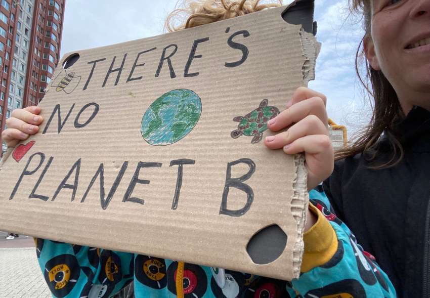 protestbord met de tekst "there's no planet B" en een getekende wereldbol en schildpad. Omhoog gehouden door onze toen 8-jarige in Rotterdam